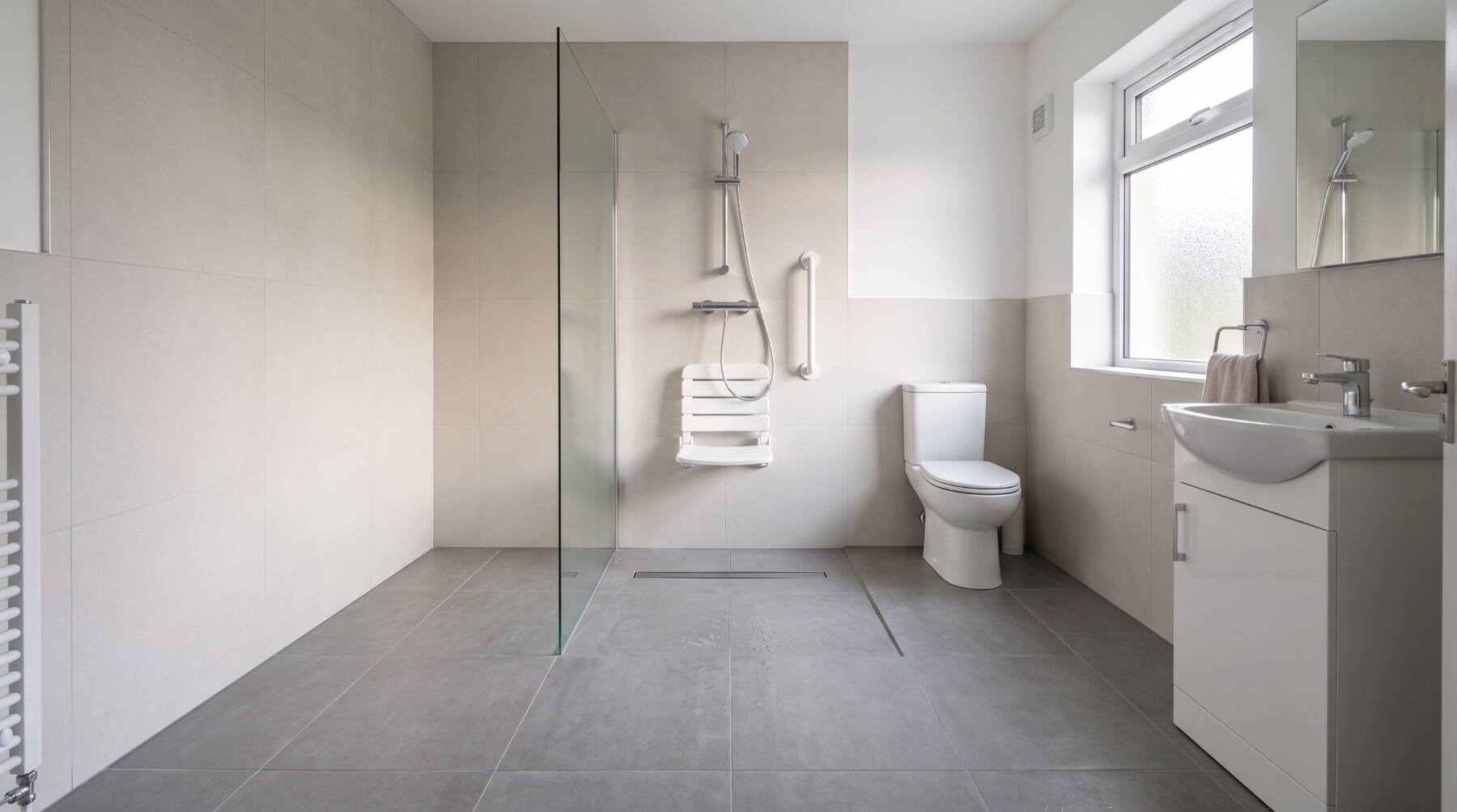 A level-access wet room with a fold-down shower seat and grab rail in an Irish home
